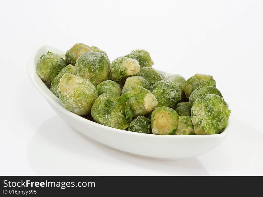 Frozen Brussels sprouts in a bowl on bright background