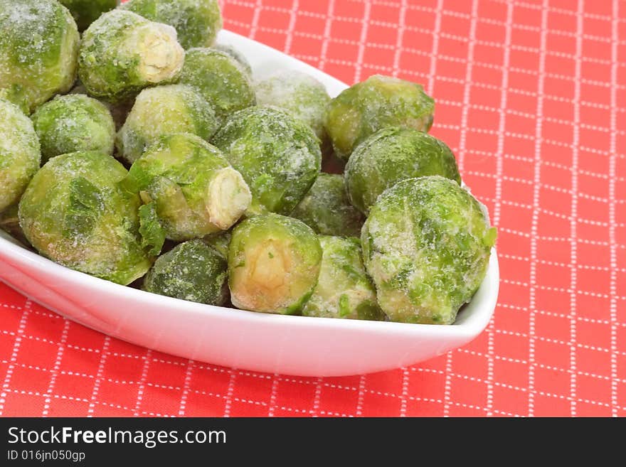 Frozen Brussels sprouts in a bowl on red background