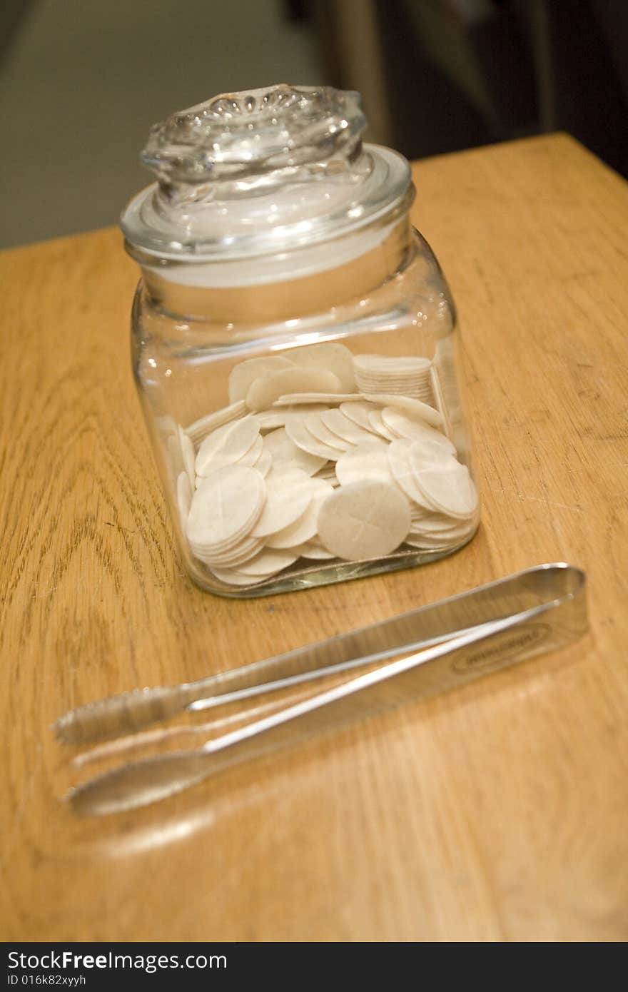 Communion wafers sitting on a wooden table with silver tongs