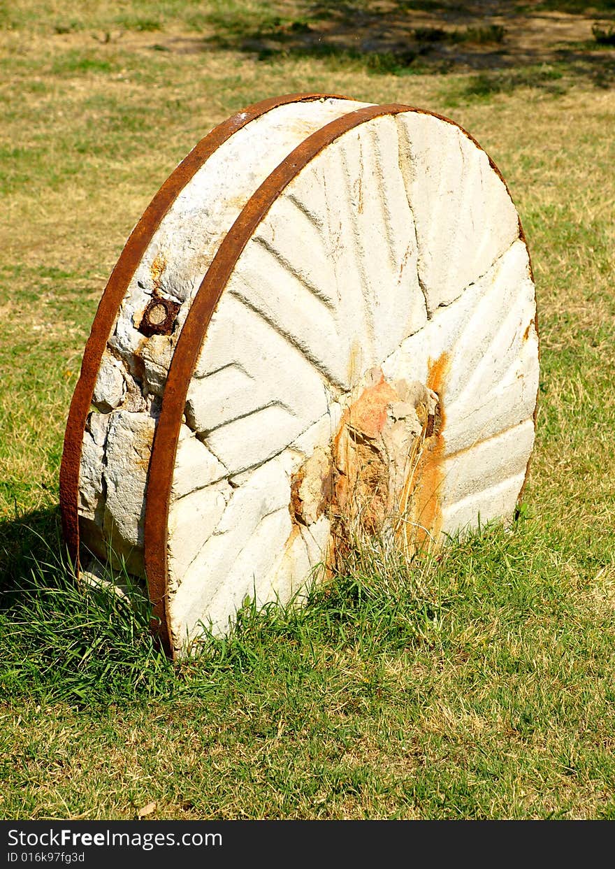 A beautiful close up of an old millstone buried in a field. A beautiful close up of an old millstone buried in a field