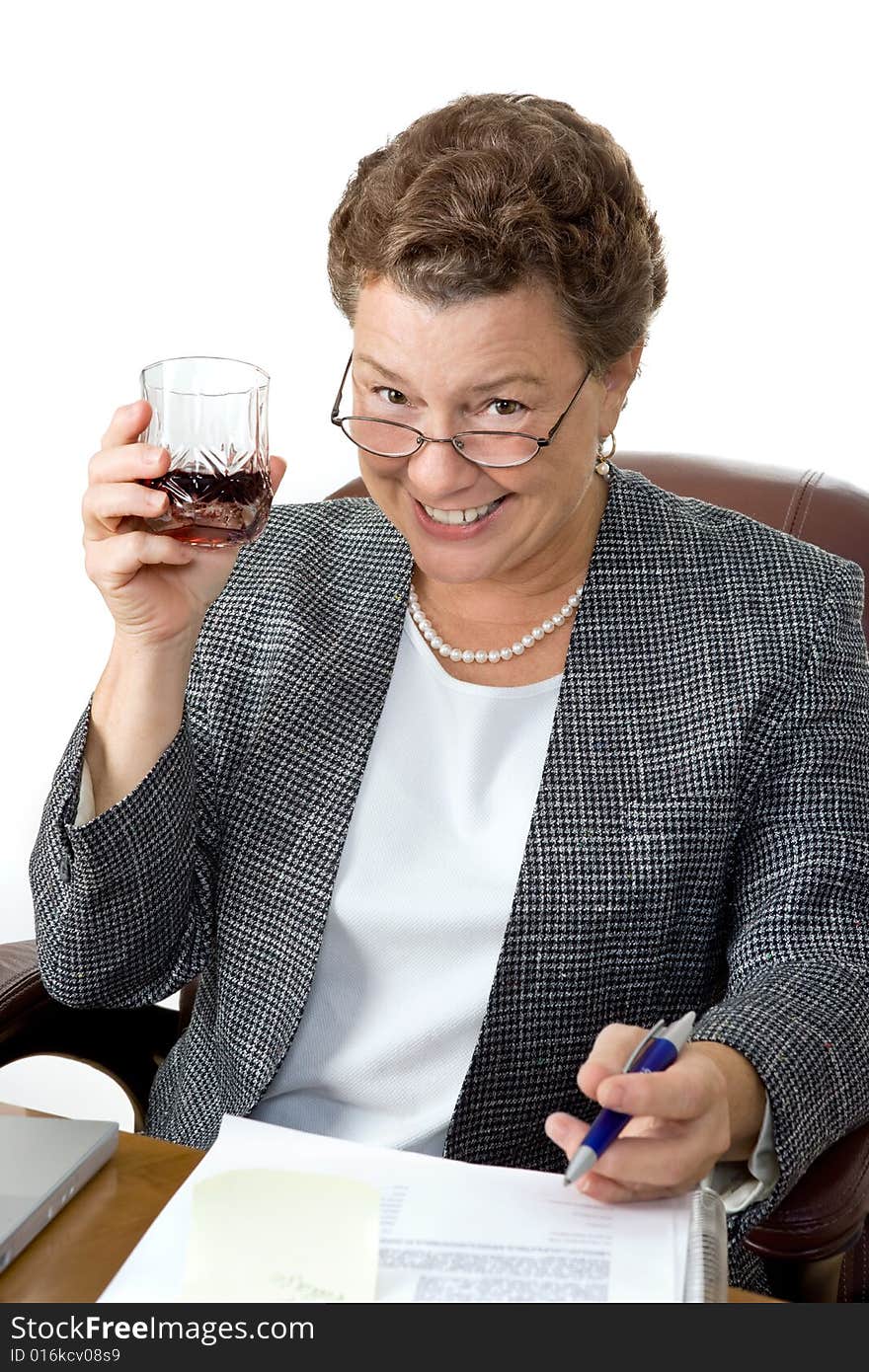 A mature businesswoman drinking on the job, office setting.