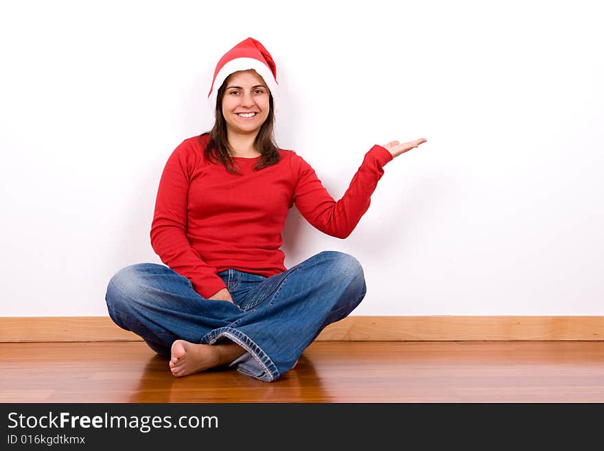 Young woman with red christmas hat sitting in house floor