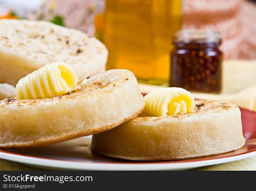 Two hot crumpets on a plate (jam in the background). Two hot crumpets on a plate (jam in the background)