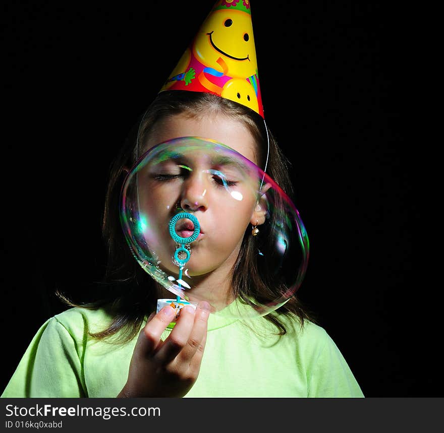 Little girl blowing soap bubbles, children's birthday party