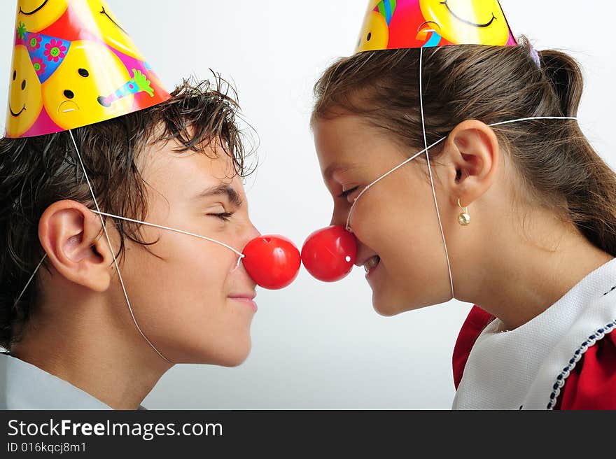 A little girl and a boy with party horn and clown noses