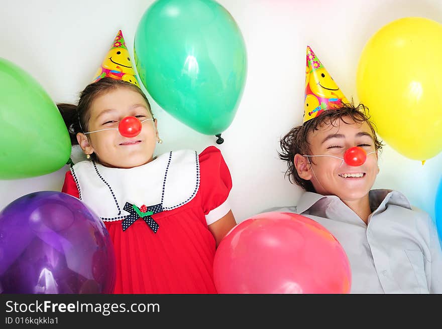 A little girl and a boy with party horn and clown noses