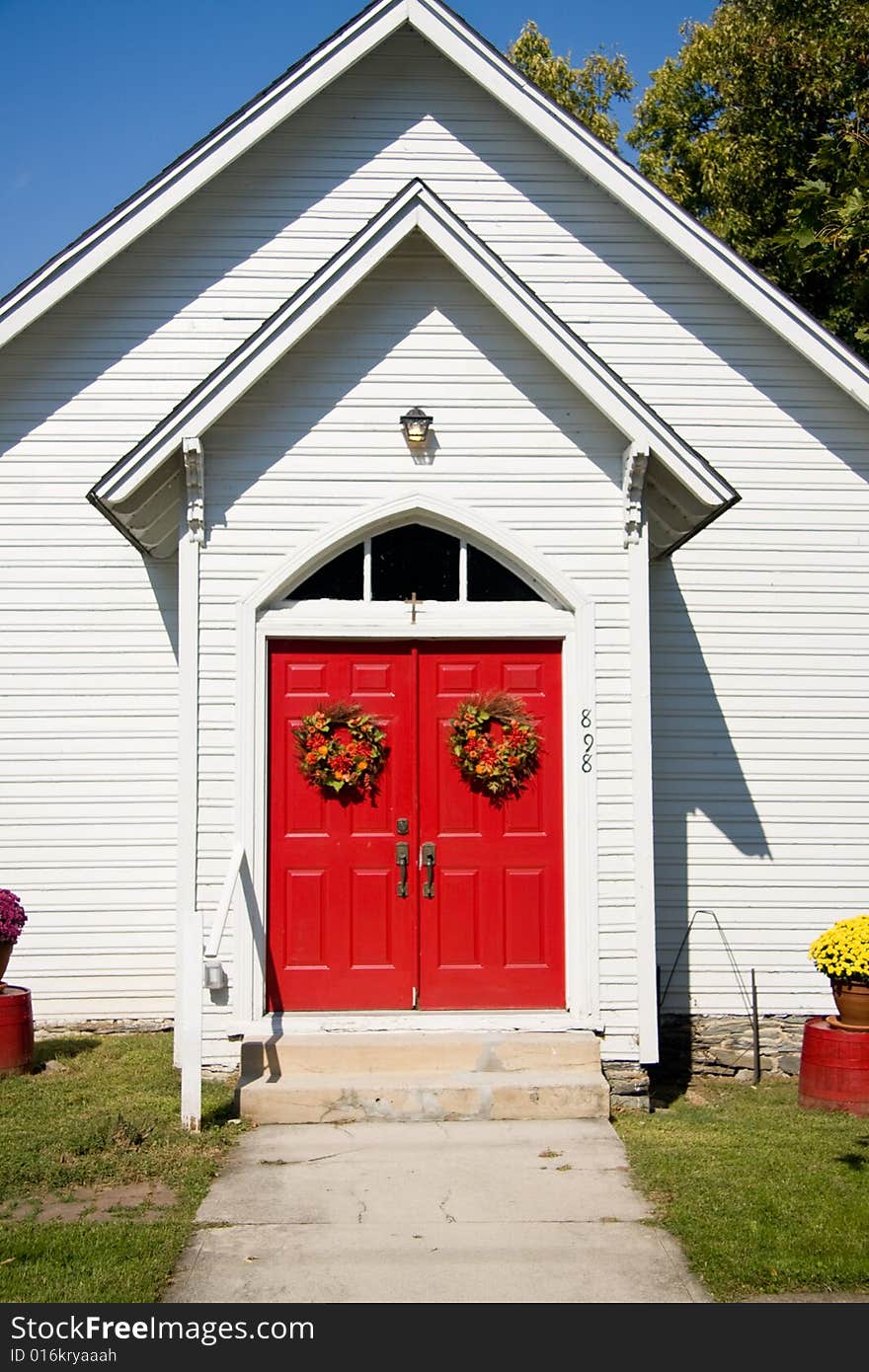 View of bright red church doors decorated with fall wreaths. View of bright red church doors decorated with fall wreaths