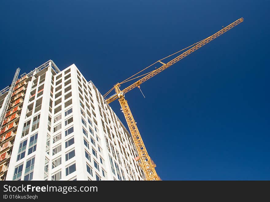 Yellow crane over white skyscraper