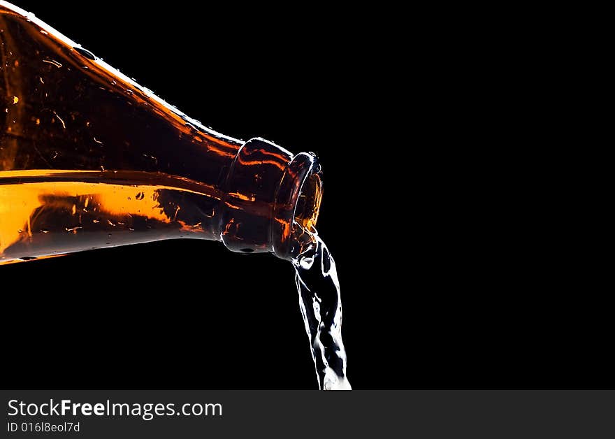 Flowing water from bottle isolated on black