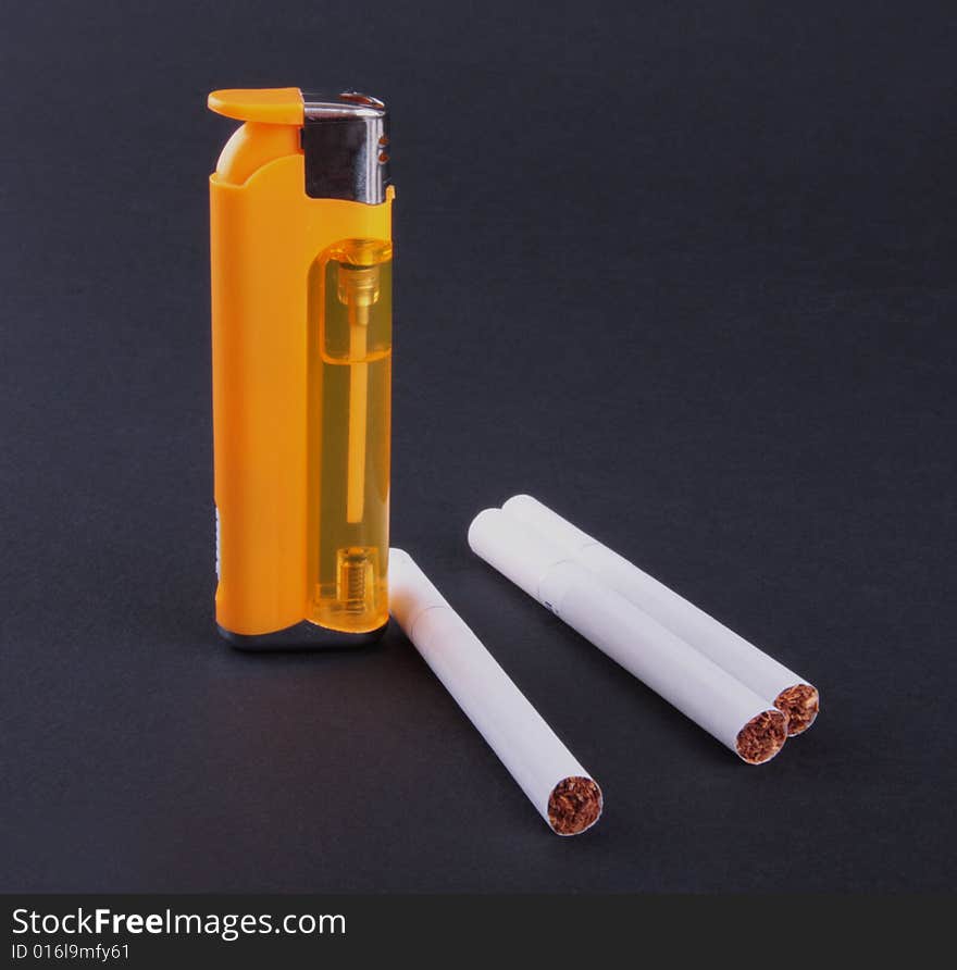 Cigarette-lighter and cigarettes isolated on dark background