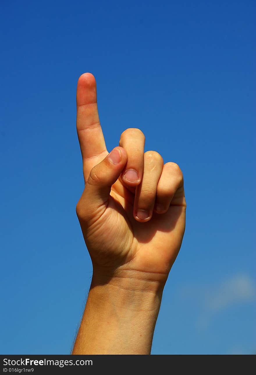 Hand pointing with index finger against a sky background