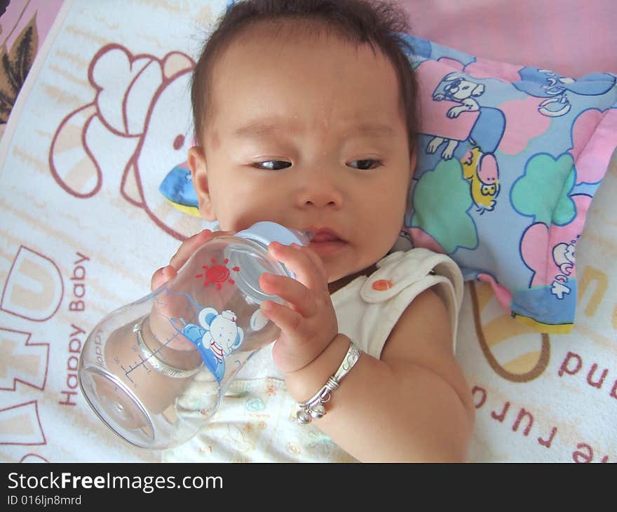 A baby is drinking water with baby's bottle. A baby is drinking water with baby's bottle