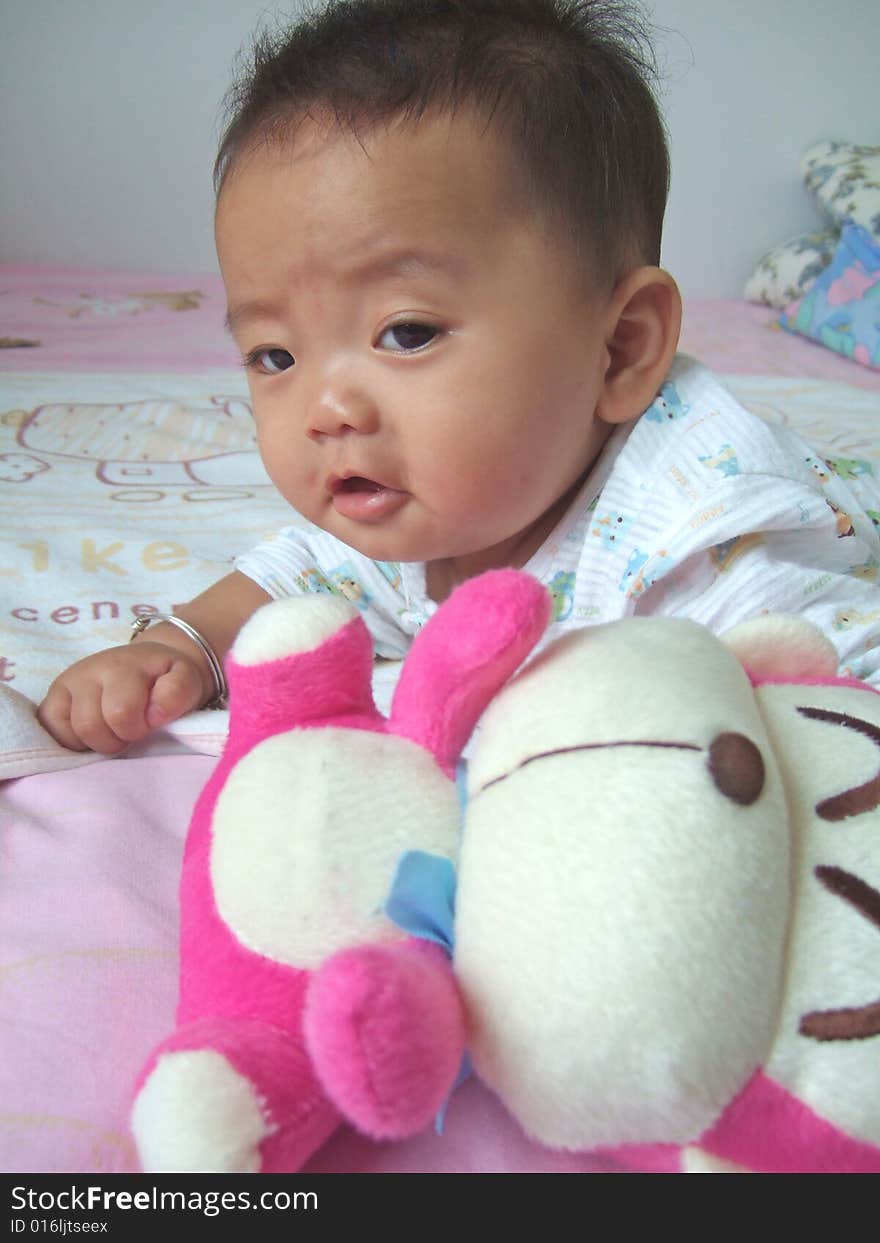 Lovely baby and toy monkey on a bed