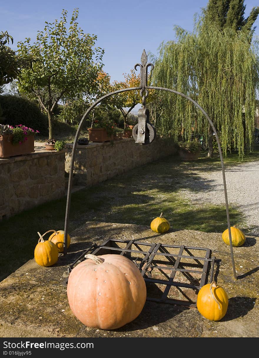 The garden of a luxury country house in the famous Tuscan hills, Italy. Pumpkins on a Well. The garden of a luxury country house in the famous Tuscan hills, Italy. Pumpkins on a Well