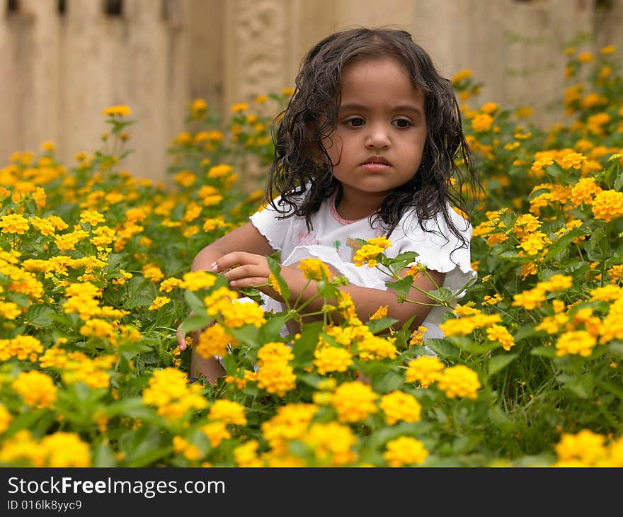 Indian girl squating inside a flower bed. Indian girl squating inside a flower bed