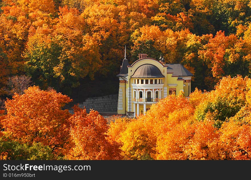 Ancient cottage among autumnal leaves. Sun weather.