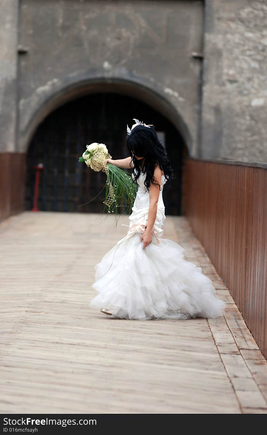 A bride looks down and hold the dress with her hand. A bride looks down and hold the dress with her hand