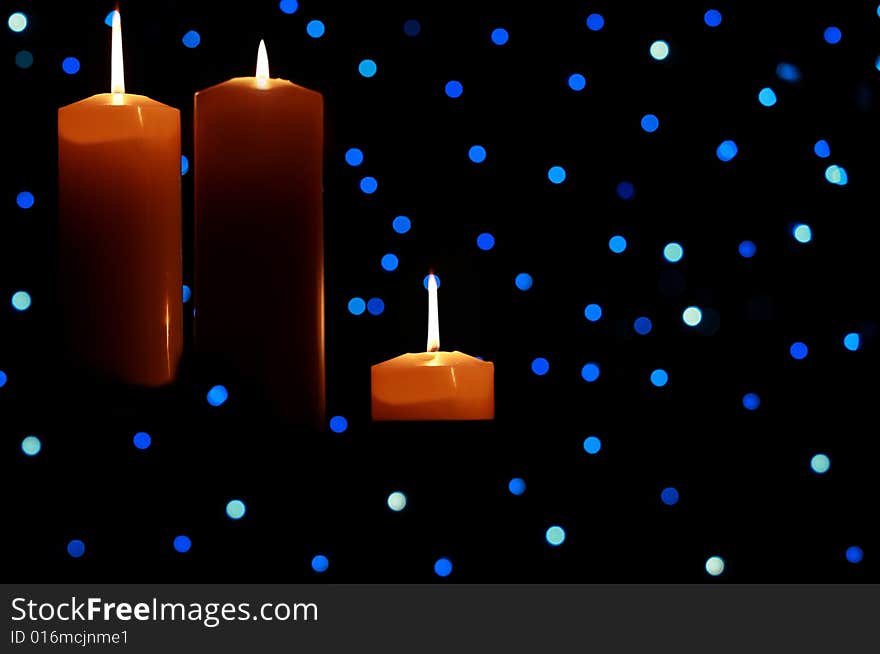 Three Large Candles Lit Amongst Blue Lights