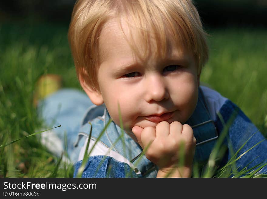 The beautiful child lays on a green grass