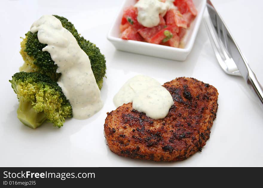 A meal of meat, broccoli and a salad of tomatoes. A meal of meat, broccoli and a salad of tomatoes