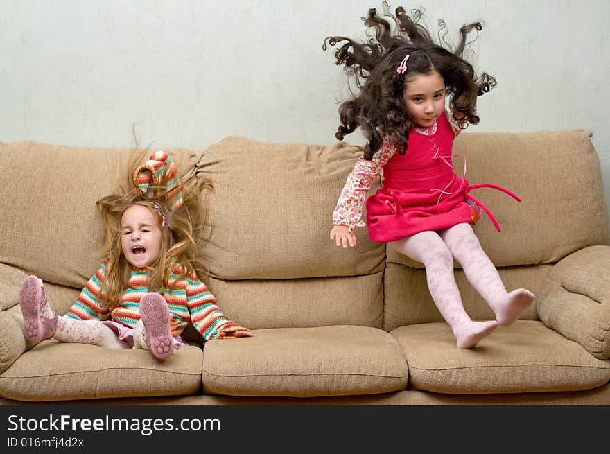 Two little girls jumping on sofa