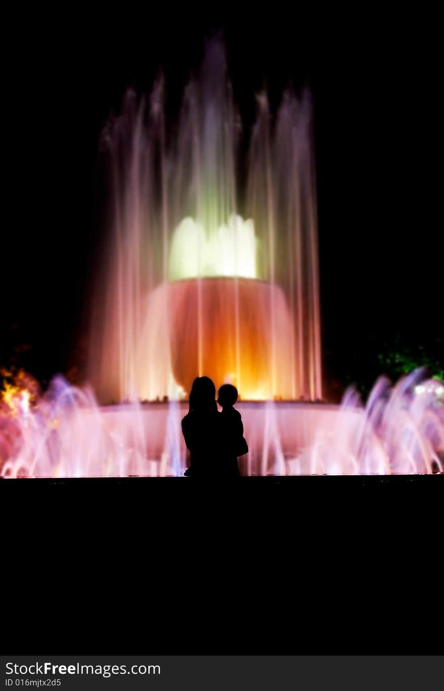 Silhouette of mother and baby over colorful fountain background. Silhouette of mother and baby over colorful fountain background