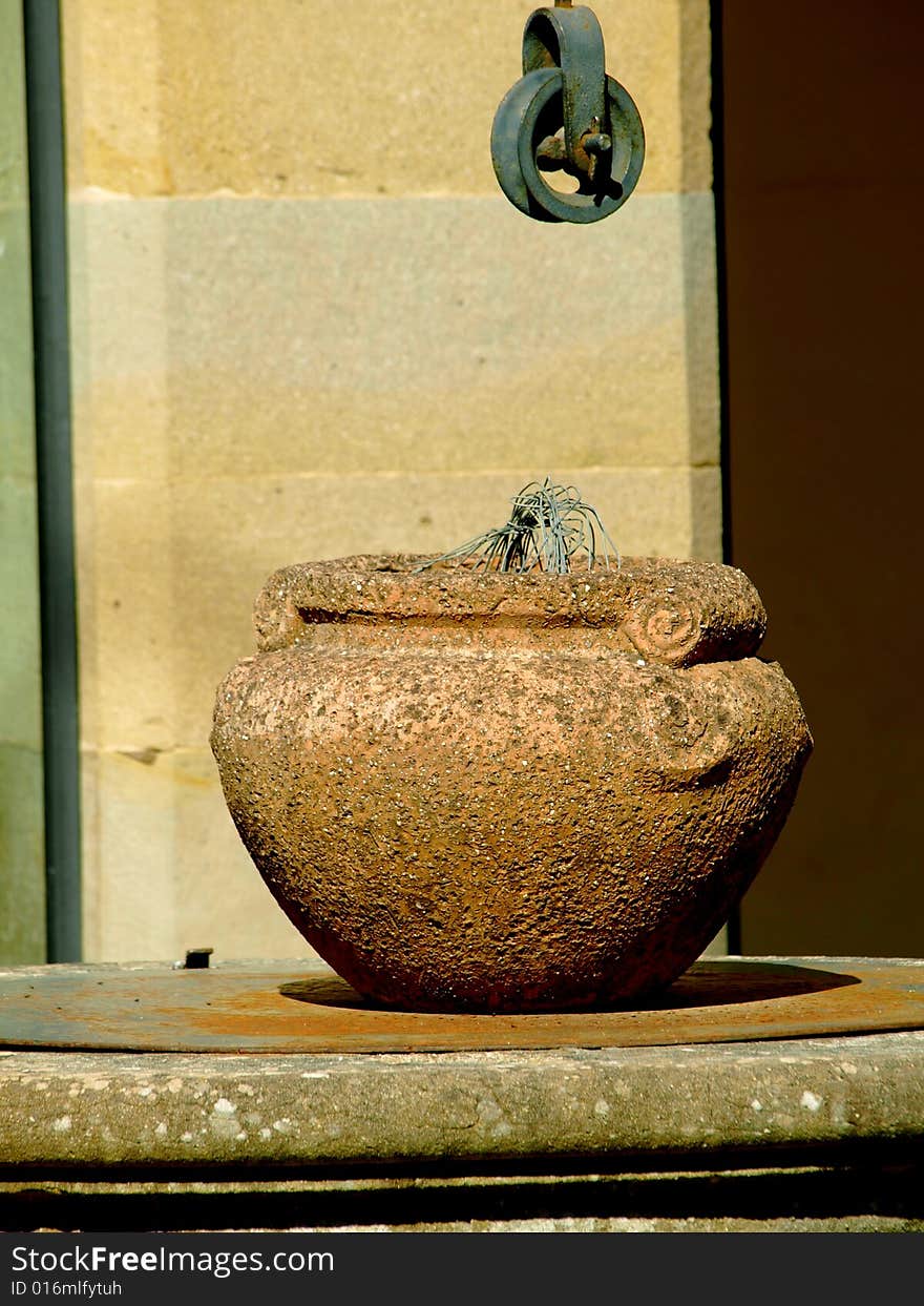 A suggestive close up of a pot over a weel in an ancient cloister. A suggestive close up of a pot over a weel in an ancient cloister