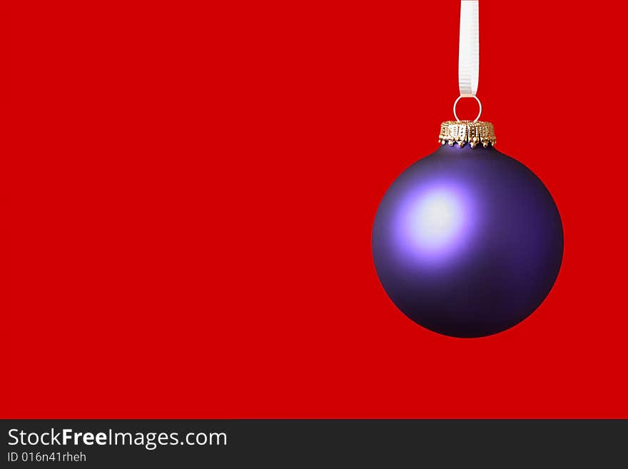 Purple christmas ornament haning on white ribbon on red background. Purple christmas ornament haning on white ribbon on red background
