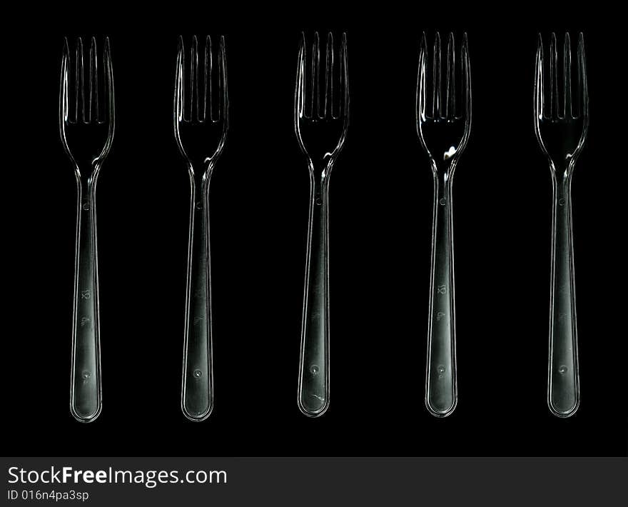 Five transparent plastic forks isolated on black