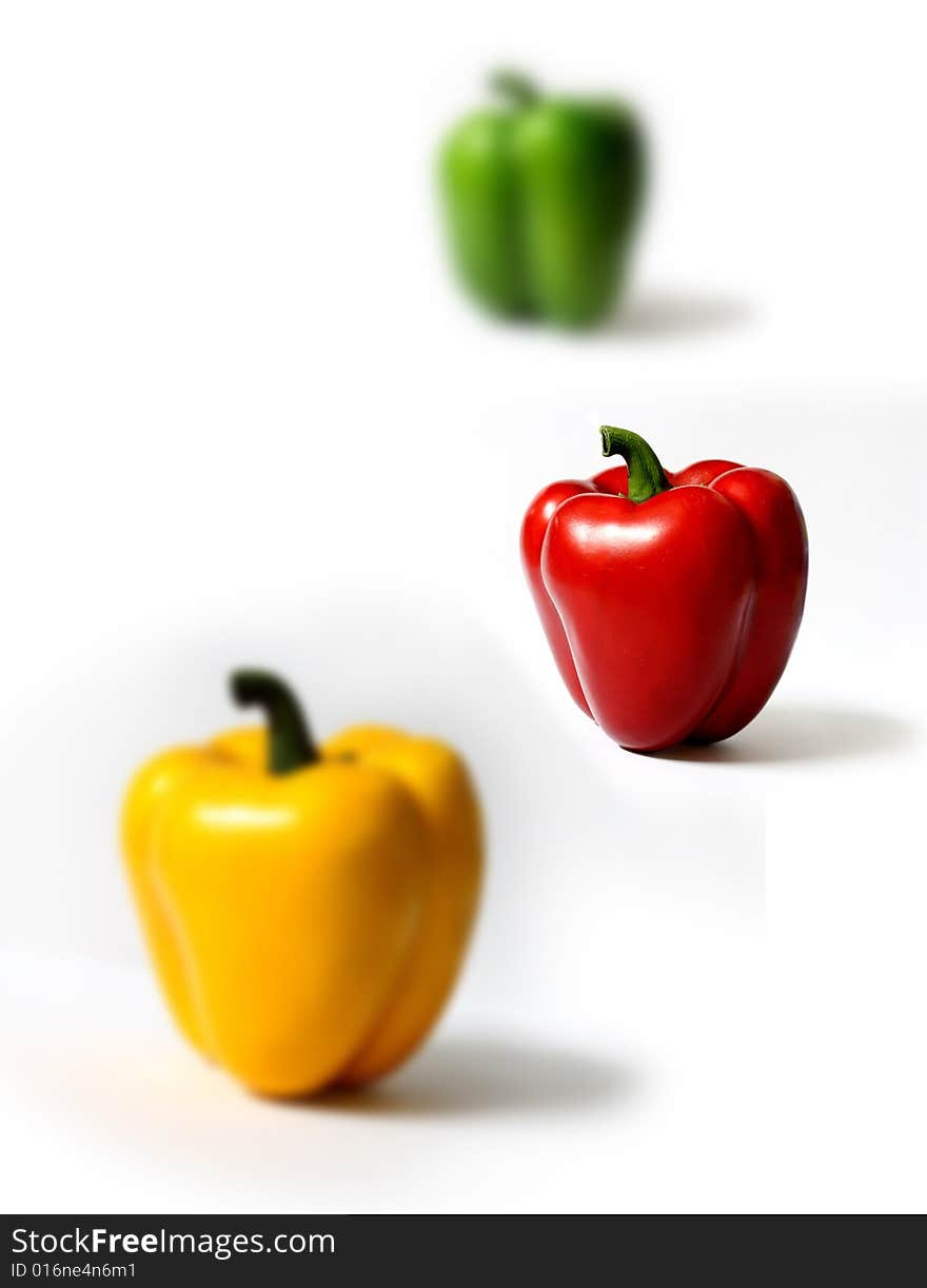 Three peppers in different colors on white background