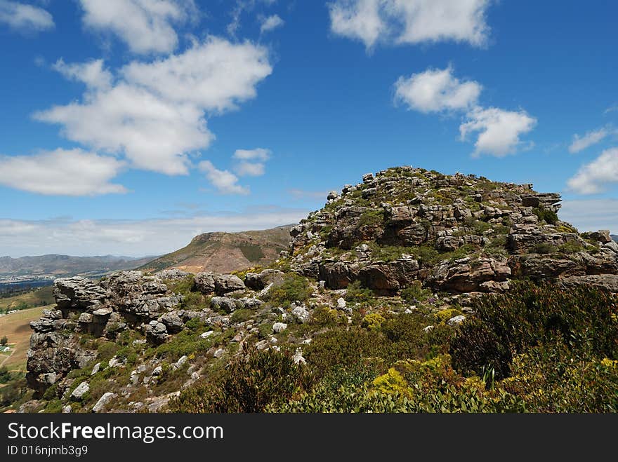 This small mountain peak is called the Eagle's Nest and is found in Cape Town, South Africa.