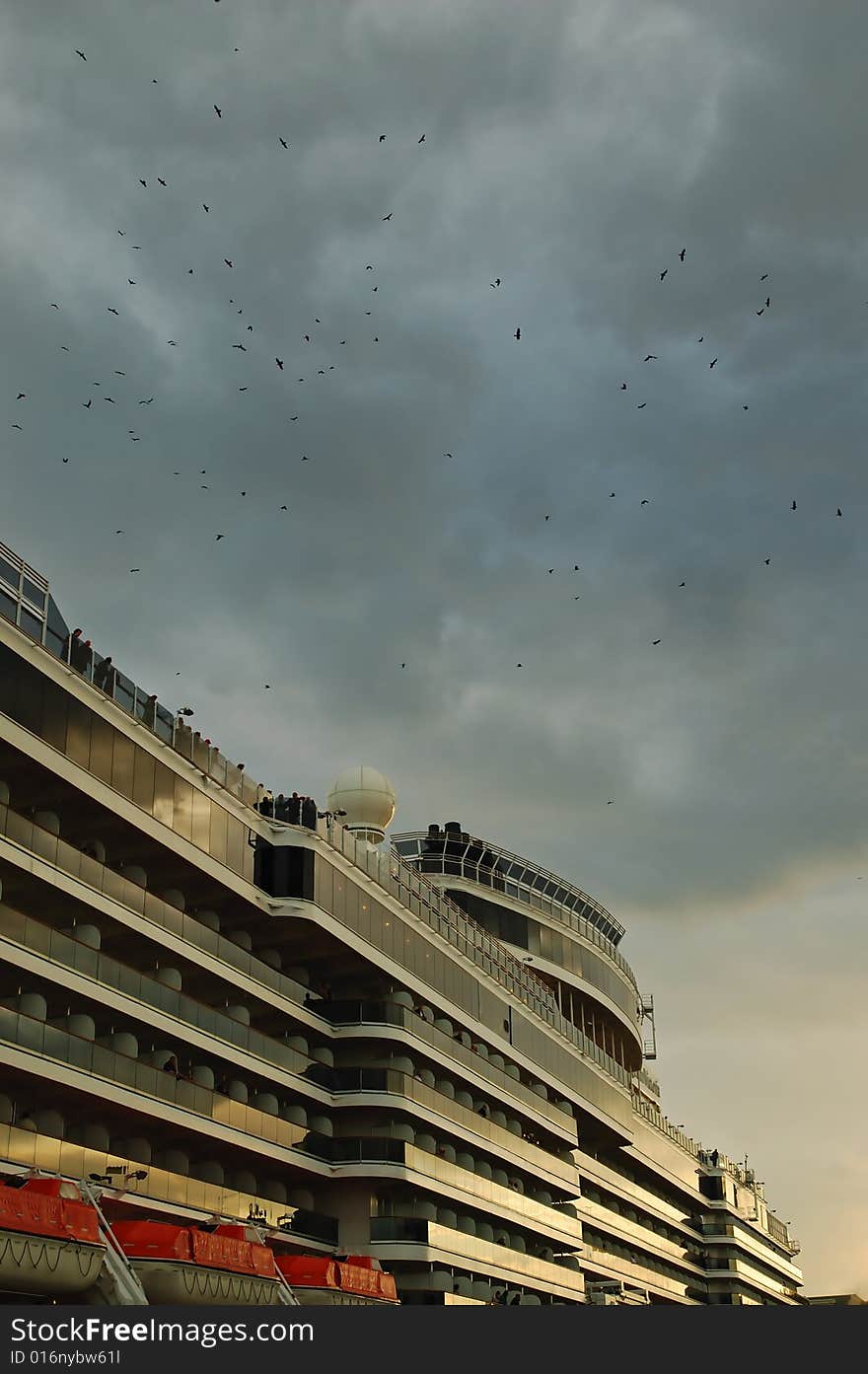 Cruise ship docked in port with birds on dramatic sky. Cruise ship docked in port with birds on dramatic sky