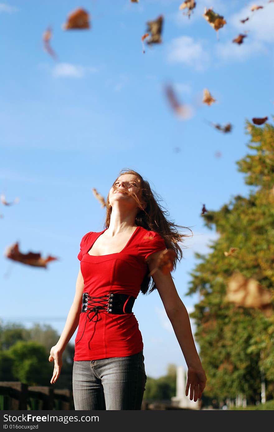 Young happy woman in red throw the maple leaf. Young happy woman in red throw the maple leaf