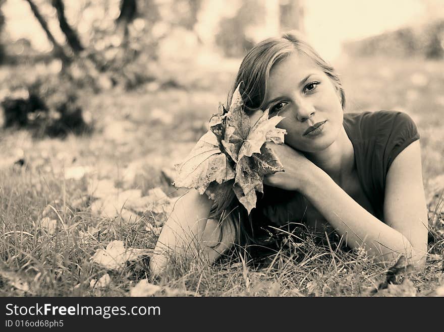 Young beautiful woman lying on the grass with maple leaf. Young beautiful woman lying on the grass with maple leaf