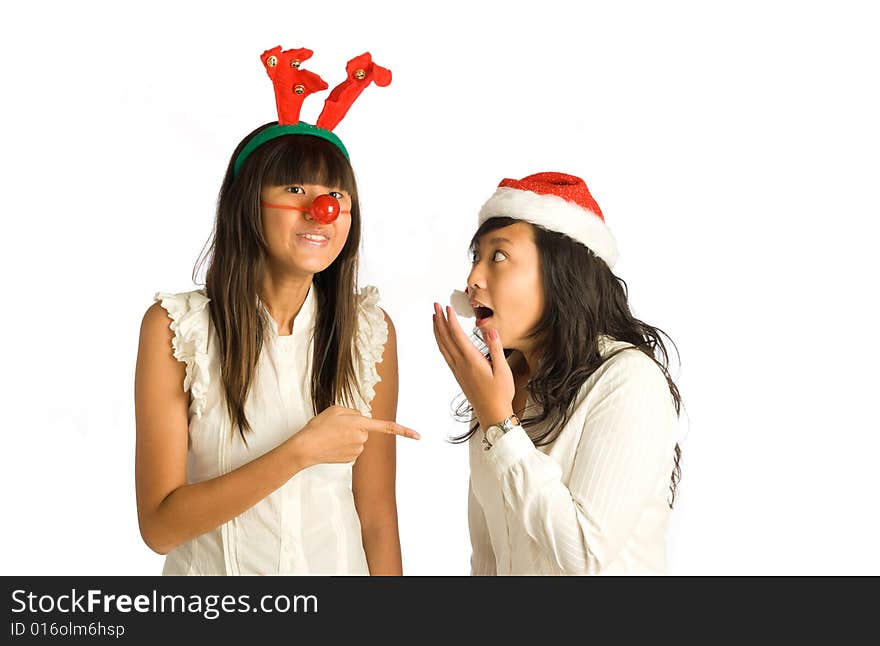 Teenager Asian girls in antlers head wear and red nose, and Santa Claus hat, having a conversation and sharing tales at a Christmas party. Teenager Asian girls in antlers head wear and red nose, and Santa Claus hat, having a conversation and sharing tales at a Christmas party.