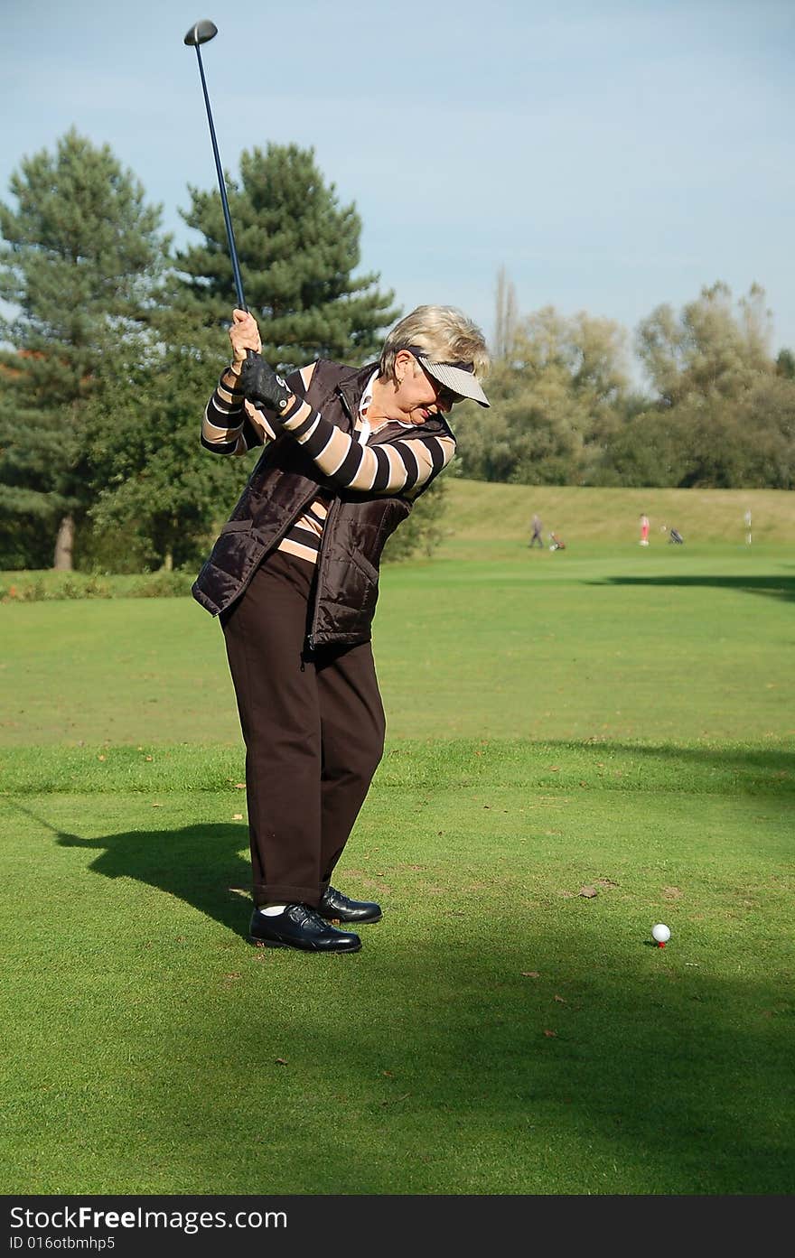 Female golfer teeing off on the green