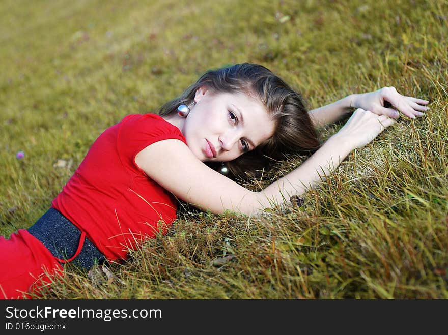 Beautiful young woman in red lying on the grass. Beautiful young woman in red lying on the grass