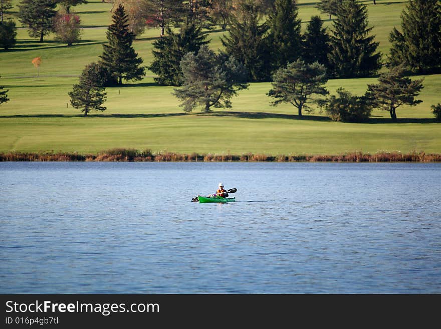 Single kayaker in a lake near golfcourse. Single kayaker in a lake near golfcourse