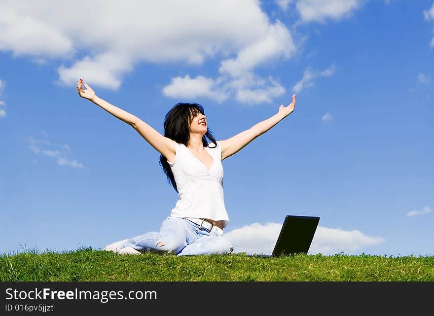 Pretty woman with laptop on the green grass