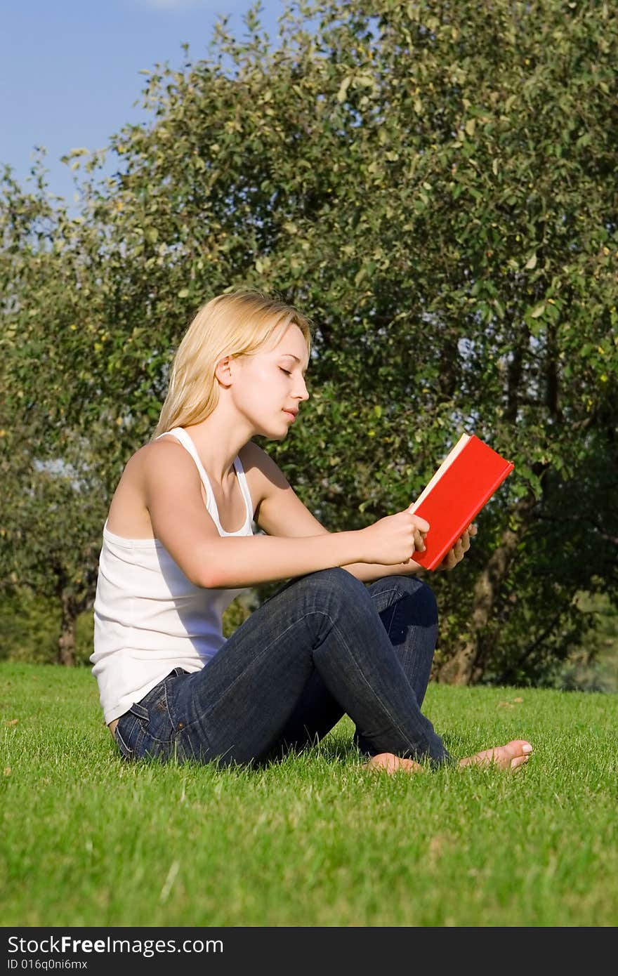 Young blonde reads book in the park