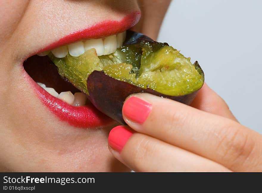 Attractive girl with red lipstick, eating a plum. Attractive girl with red lipstick, eating a plum