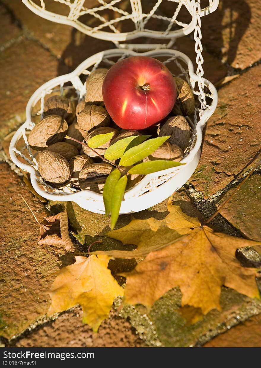 An apple and walnuts in an old white bascet