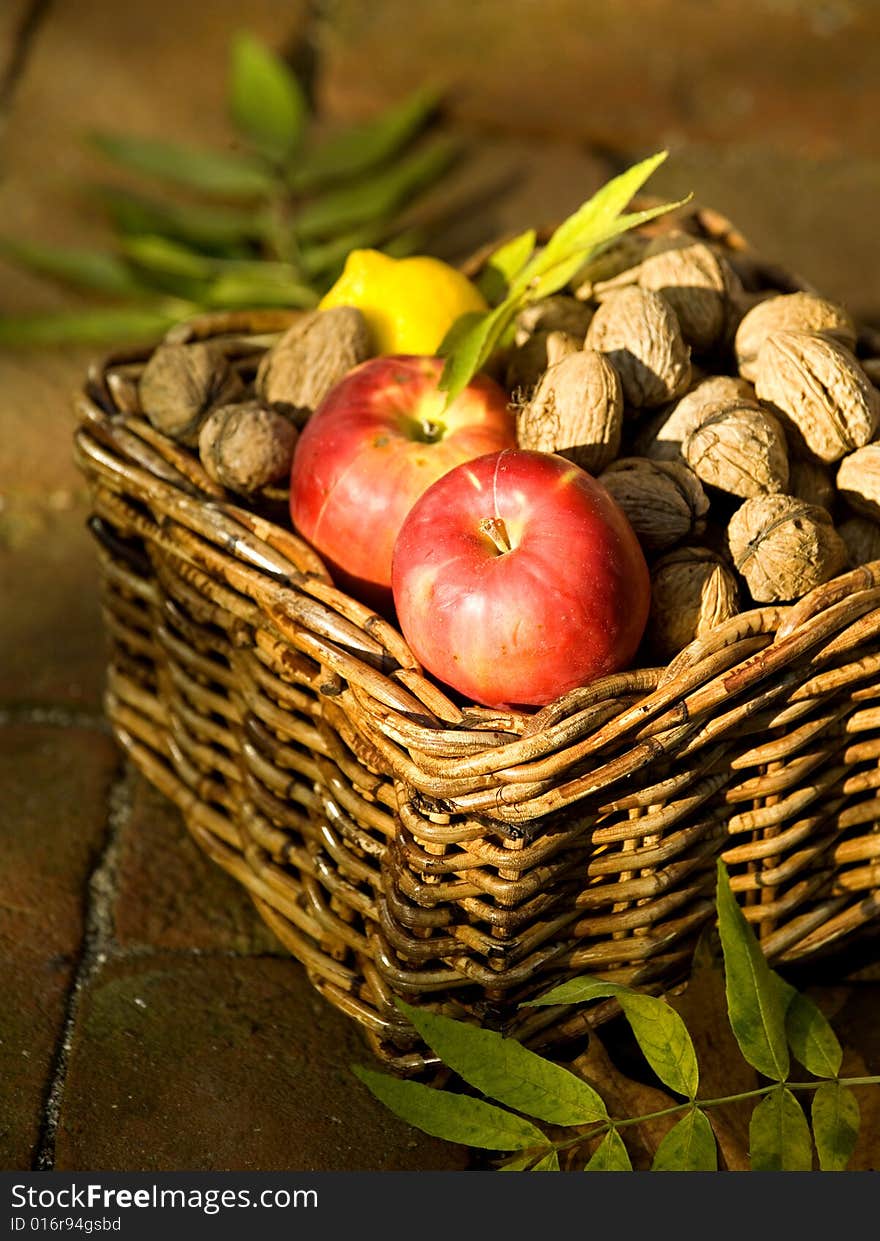 Apples and lemon with lot of walnuts in a basket. Apples and lemon with lot of walnuts in a basket