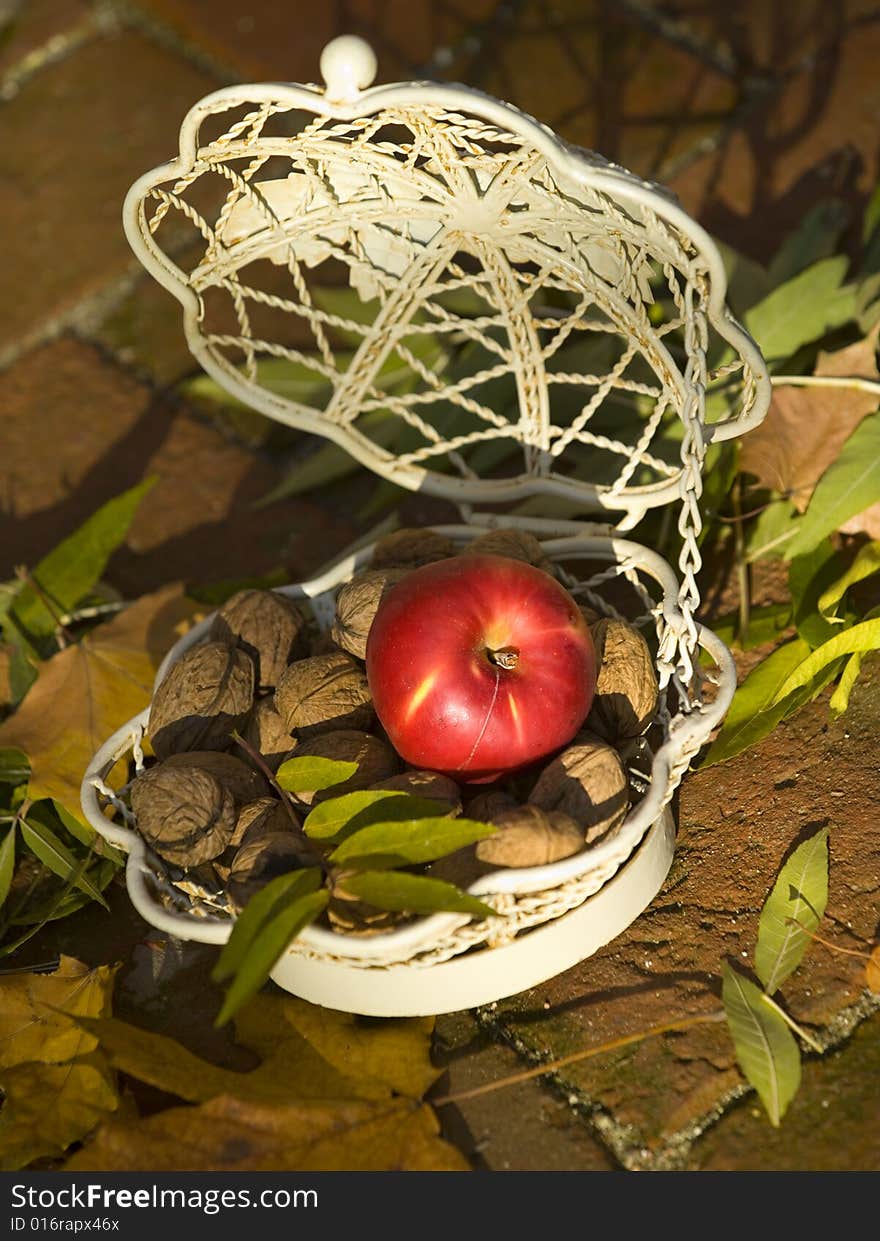 Apple with lot of walnuts in a white basket. Apple with lot of walnuts in a white basket