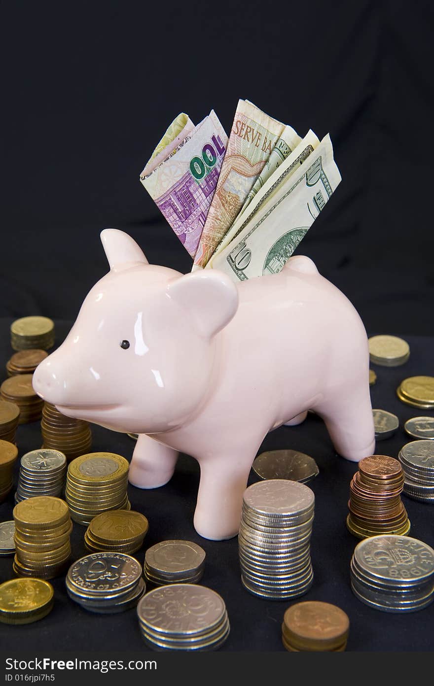 Piggy bank with various international currencies on a black background. Piggy bank with various international currencies on a black background.