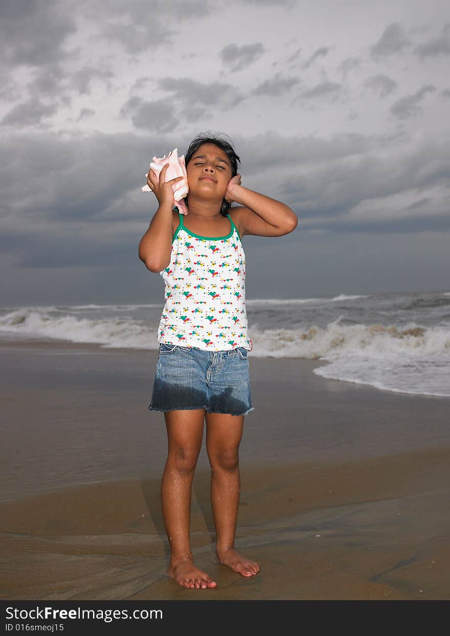 Asian girl listening to the conch in the beach