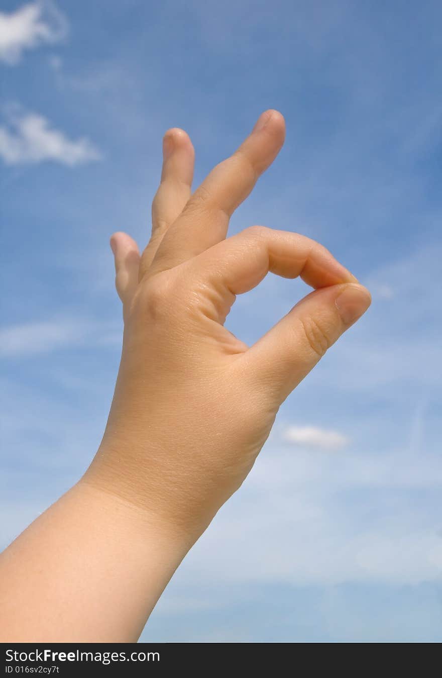 Human hand making OK sign against blue sky