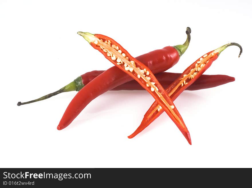 Three red chili peppers on a white background, two unimpaired and one cut open. Three red chili peppers on a white background, two unimpaired and one cut open.