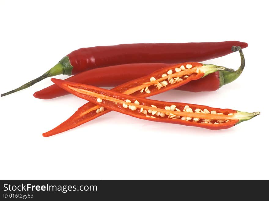 Three red chili peppers on a white background, two unimpaired and one cut open. Three red chili peppers on a white background, two unimpaired and one cut open.