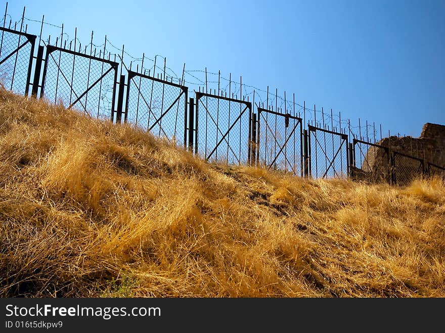 Barbed wire protects restricted area on the hill with yellow grass